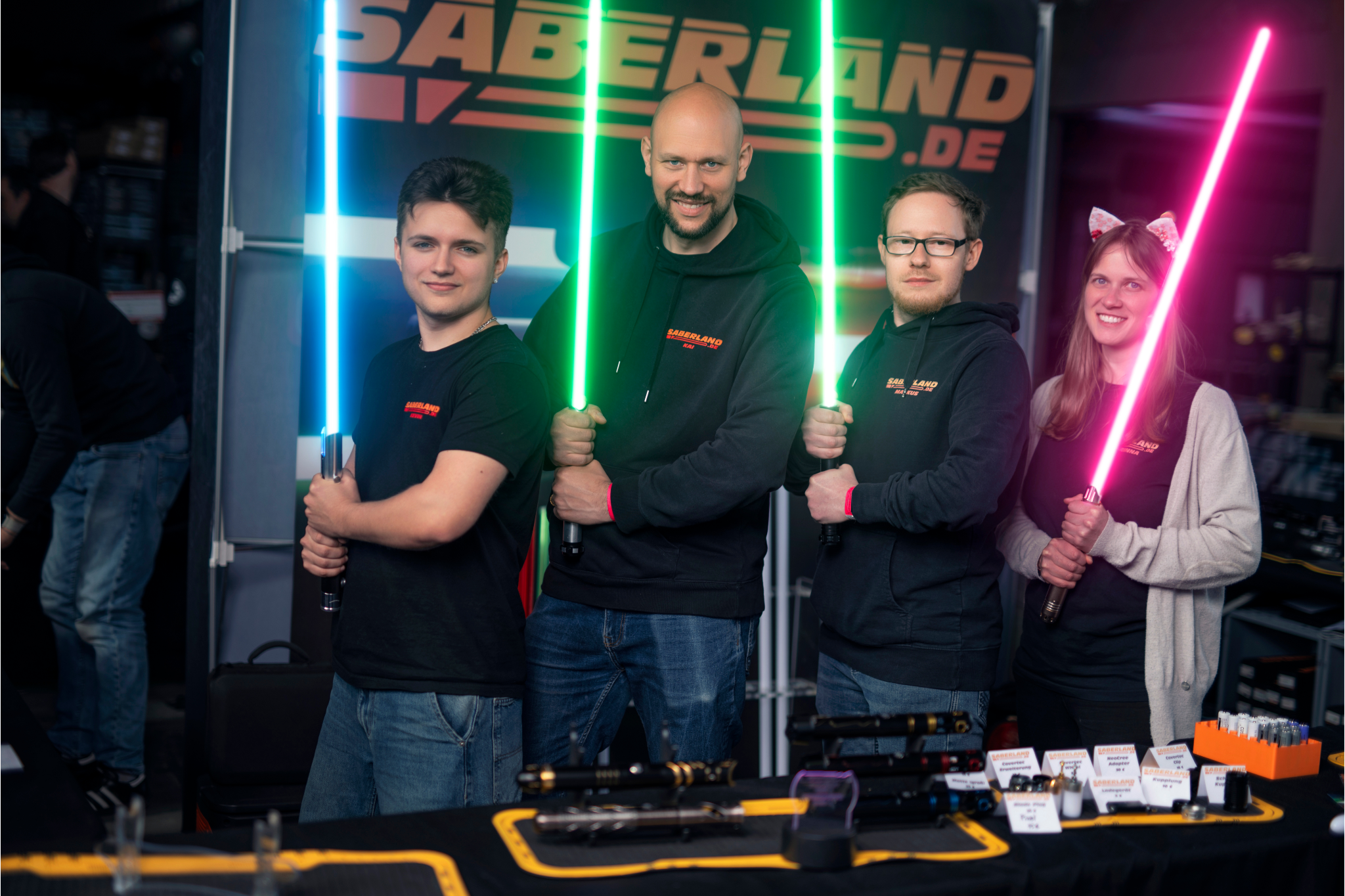 Das Sabeland-Team mit leuchtenden Lichtschwertern an ihrem Convention-Stand